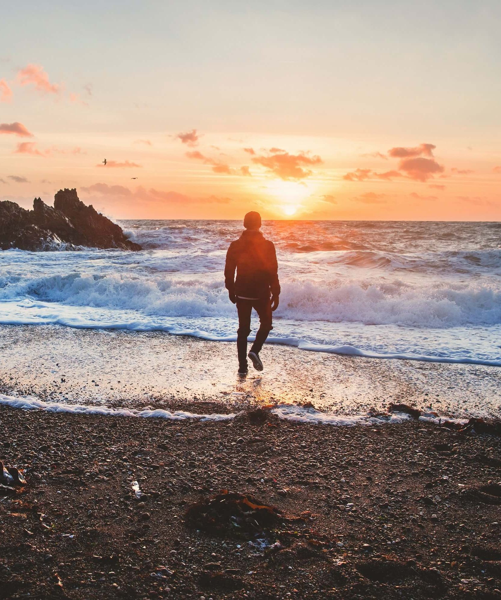 Person walking on beach at sunset