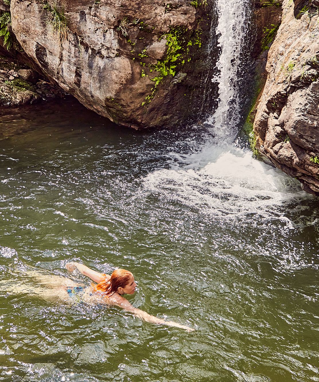 Woman swimming in waterfall pool