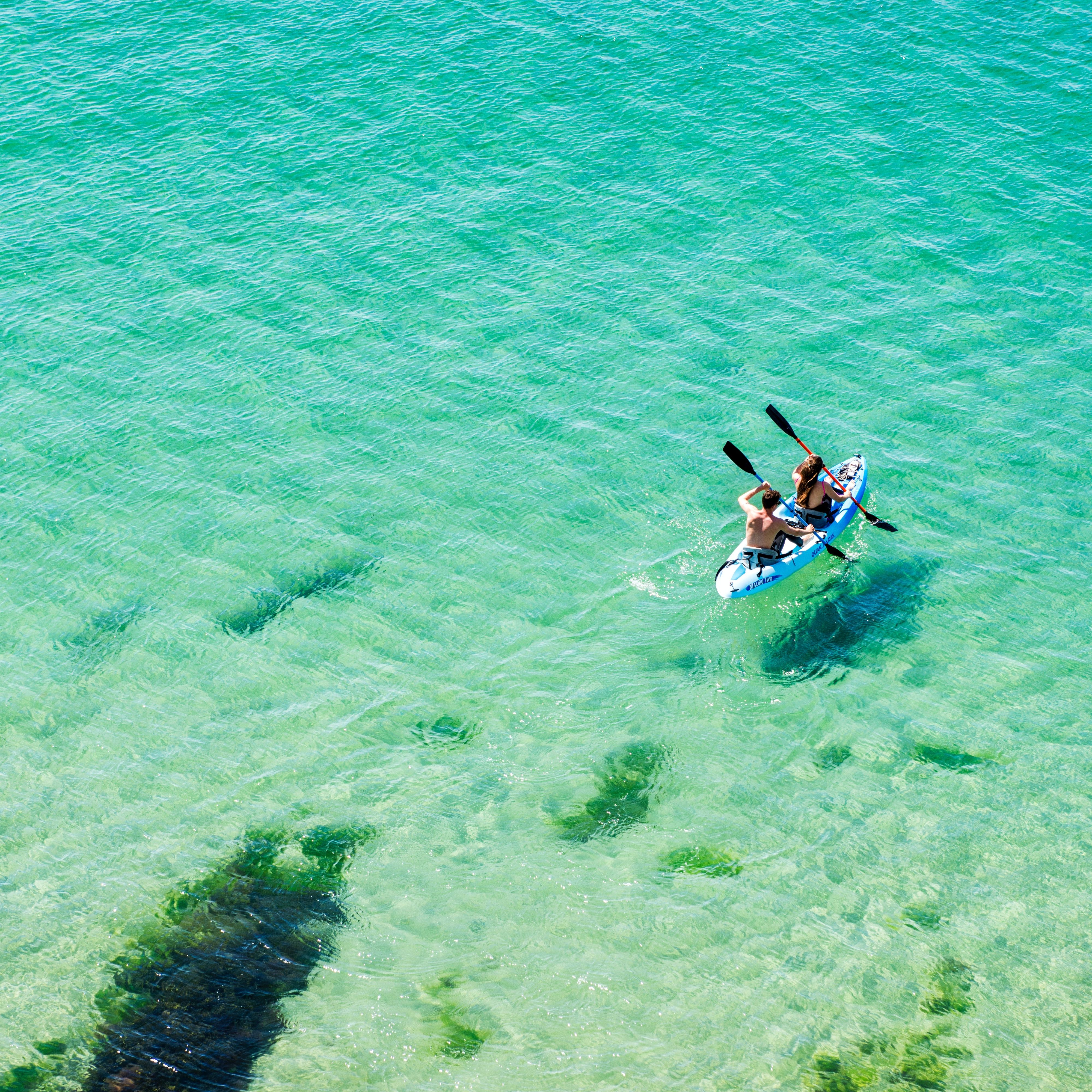 People kayaking on clear turquoise sea