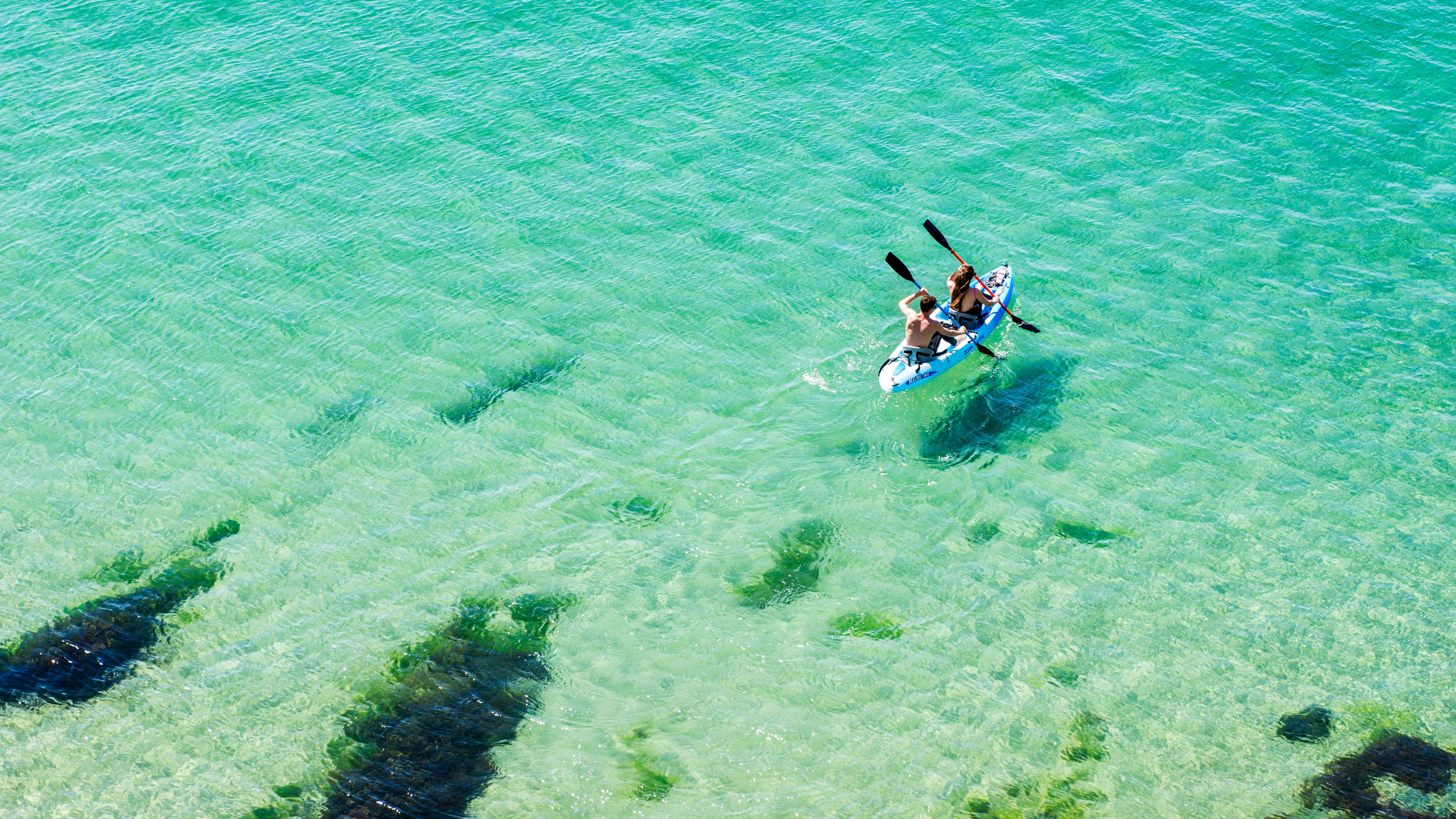 People kayaking on clear turquoise sea