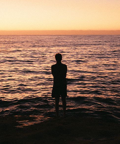 Person stood in sea at sunset