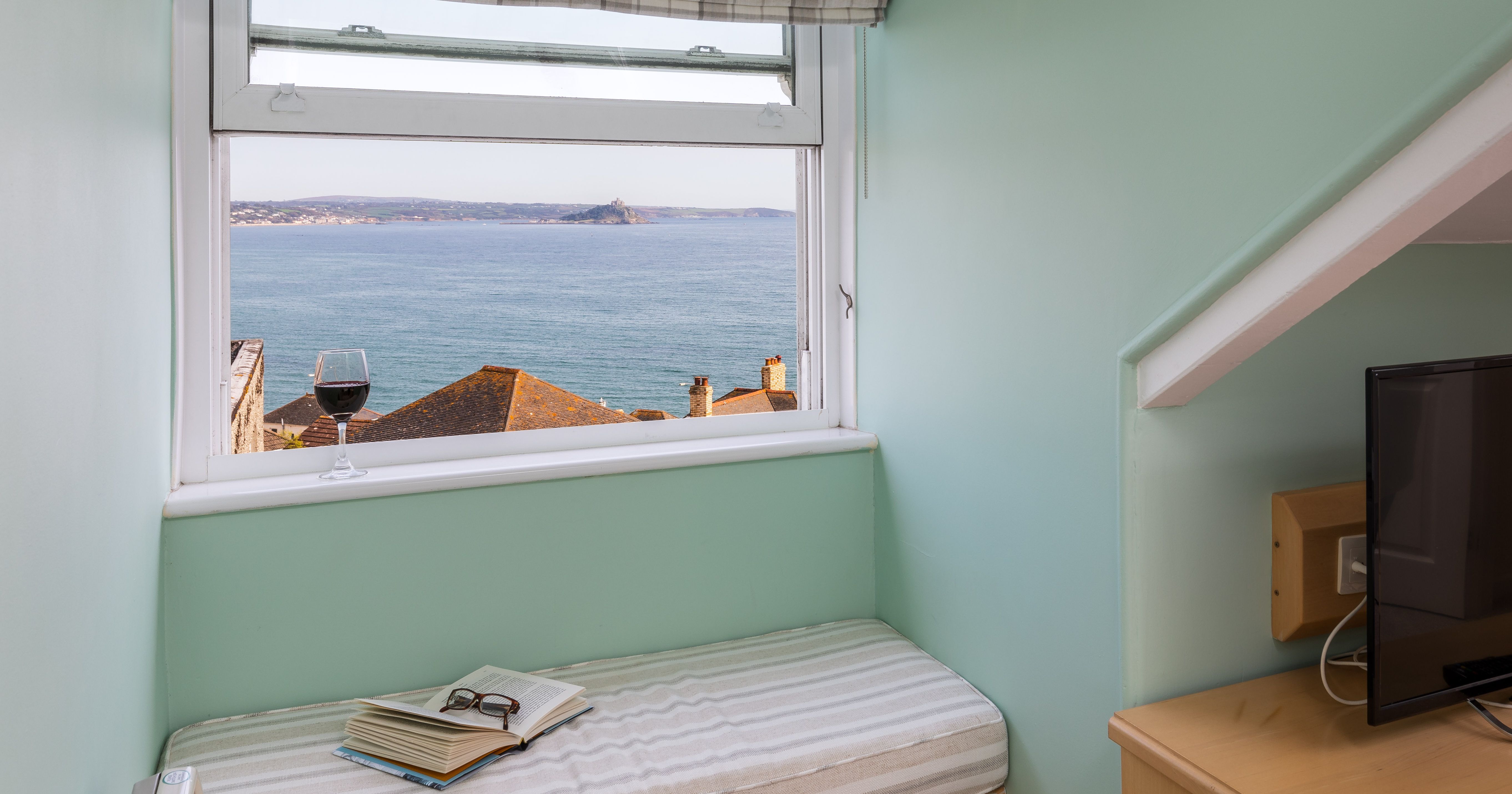 Sea views from window with glass of wine and book