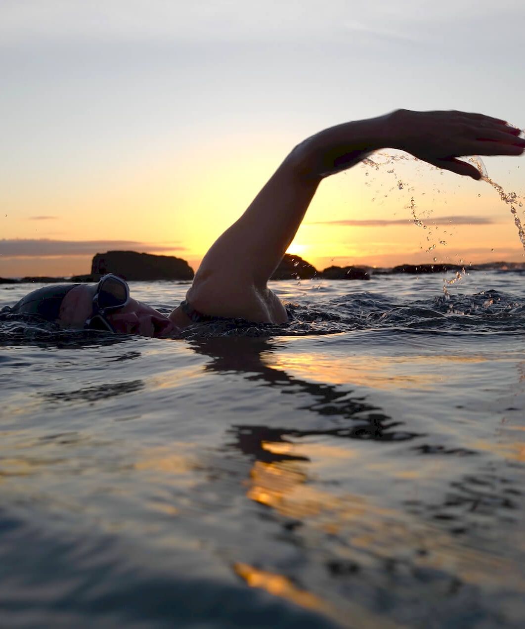 Person swimming in sea at sunset
