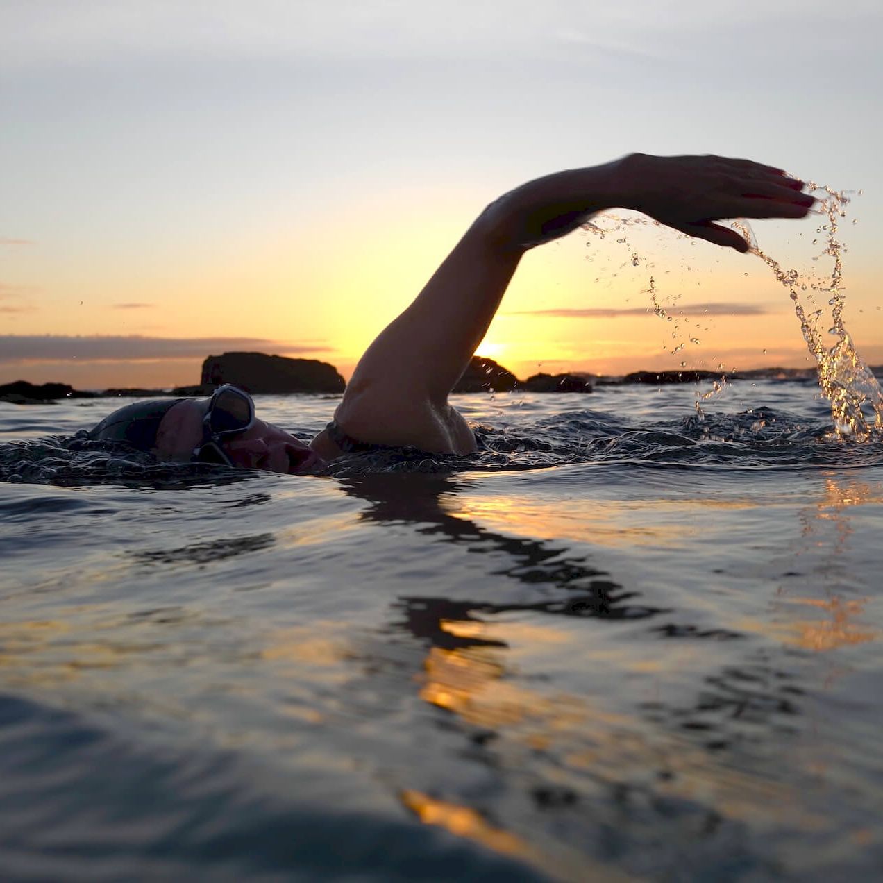 Person swimming in sea at sunset